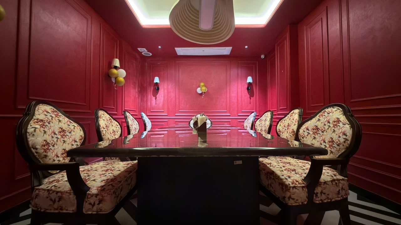 Private dining room with deep red panelled walls, floral chairs, and a dark marble table.
